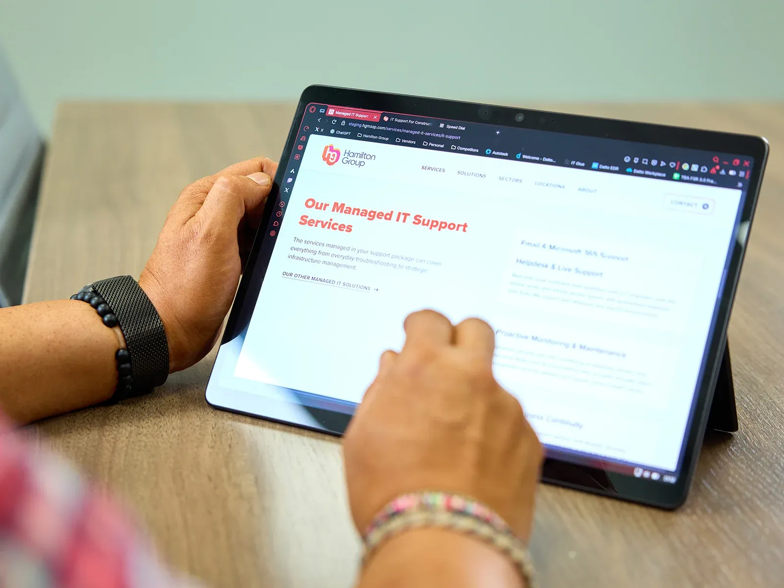Person browsing the Hamilton Group Managed IT Support Services page on a tablet.