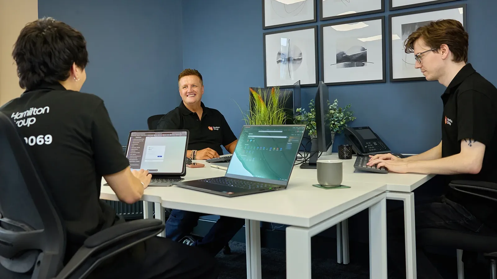 Hamilton Group team collaborating in a modern office with laptops and computers.