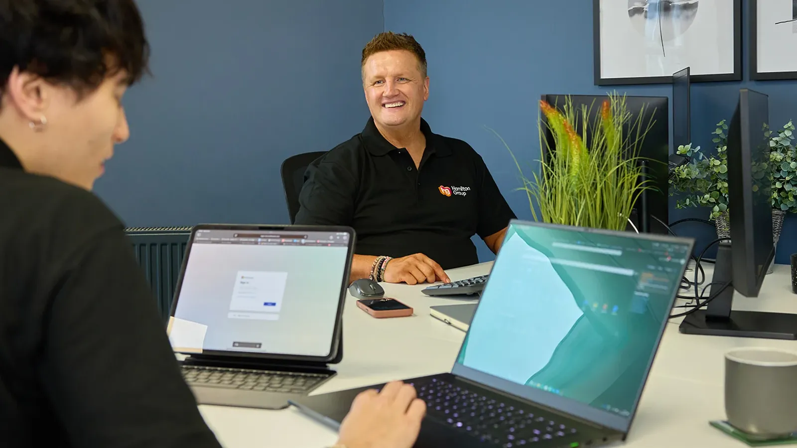 Two people collaborating at a table with laptops in a modern office.